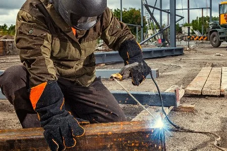 Person schweißt Metallträger auf Baustelle